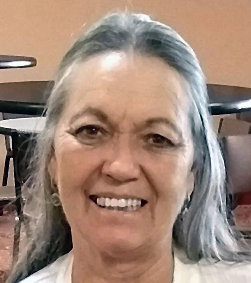 Marcene, owner of Grandma's Dog House, smiling with a small dog